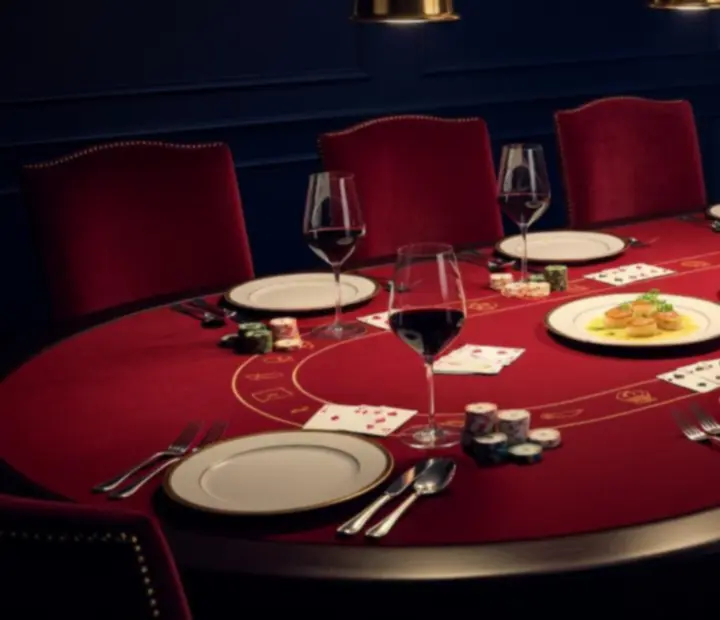 Chef's table set along a custom poker table with plated dishes and entertainment chips